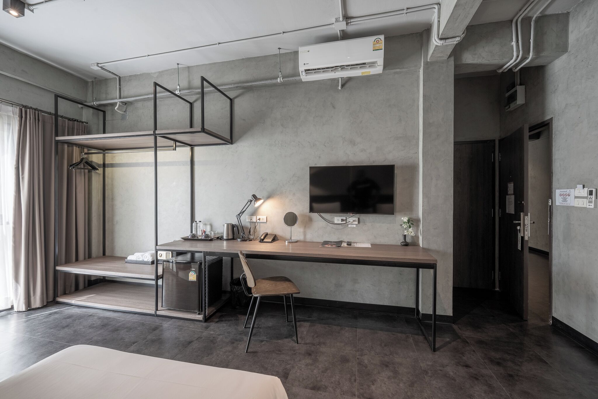 Une chambre d’hôtel moderne équipée d’un lit superposé, d’un bureau avec une chaise, d’une télévision et d’un appareil de climatisation.