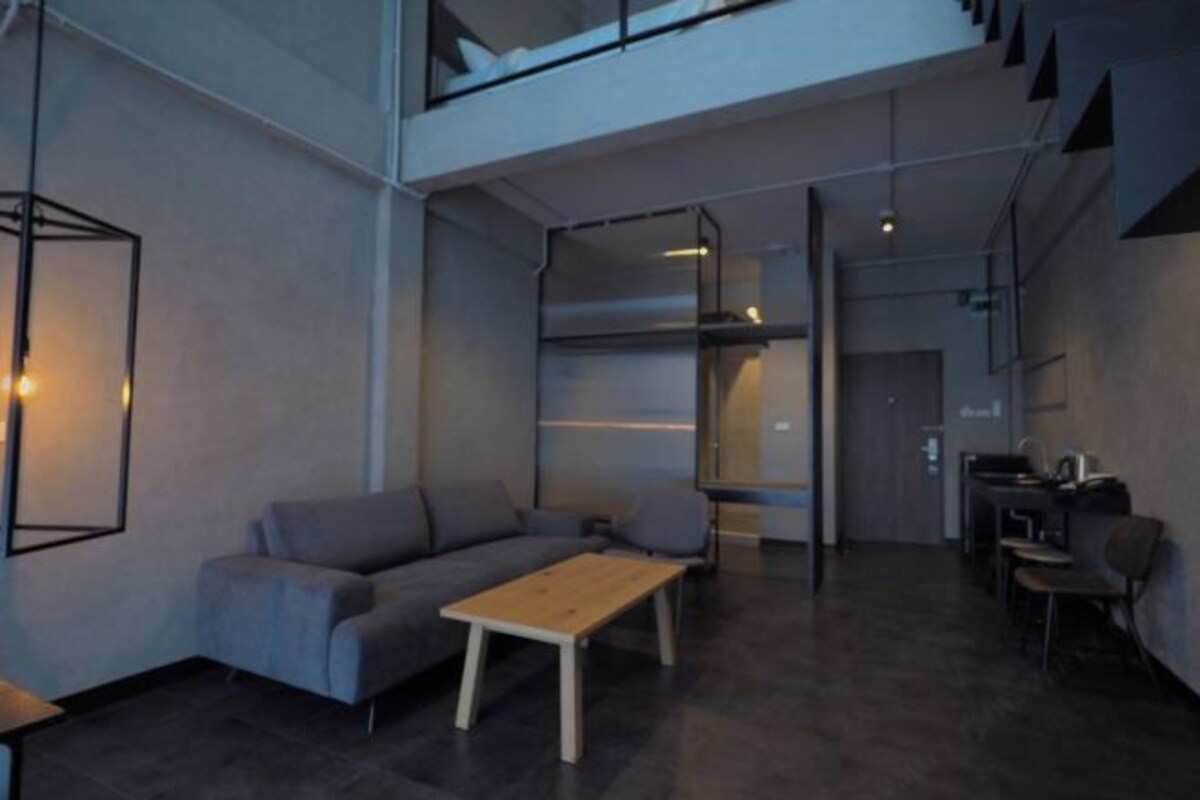 A modern interior with a sofa, a wooden table, and a dining area.