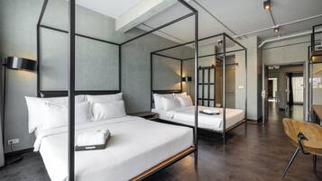 Una habitación de hotel moderna con una cama con dosel, una cama individual, un escritorio con silla y un baño a la vista.