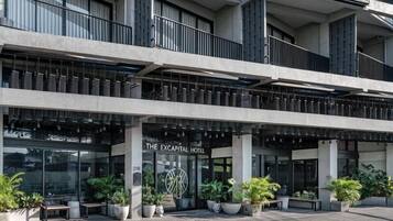 A modern hotel with a prominent entrance, multiple balconies, and potted plants.