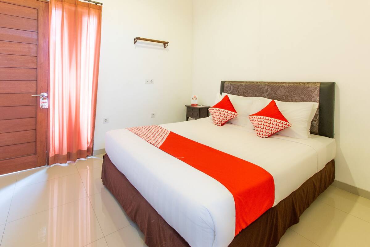 A hotel room with a large bed, a wooden door, and a curtain.