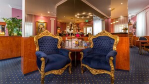 A luxurious hotel lobby with two ornate blue velvet chairs, a reception desk, and a decorative mirror. - Hotel Atlanta Budget (Darmstadt)