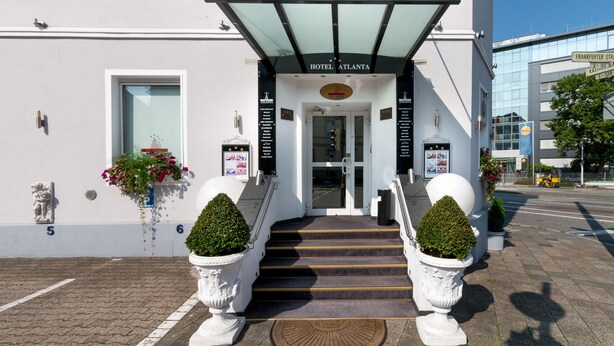 A hotel entrance with a covered entrance, steps, and potted plants. - Hotel Atlanta Budget (Darmstadt)