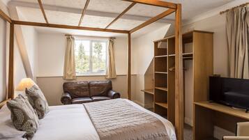 Un dormitorio con una cama con dosel, un televisor sobre un escritorio de madera y un armario.