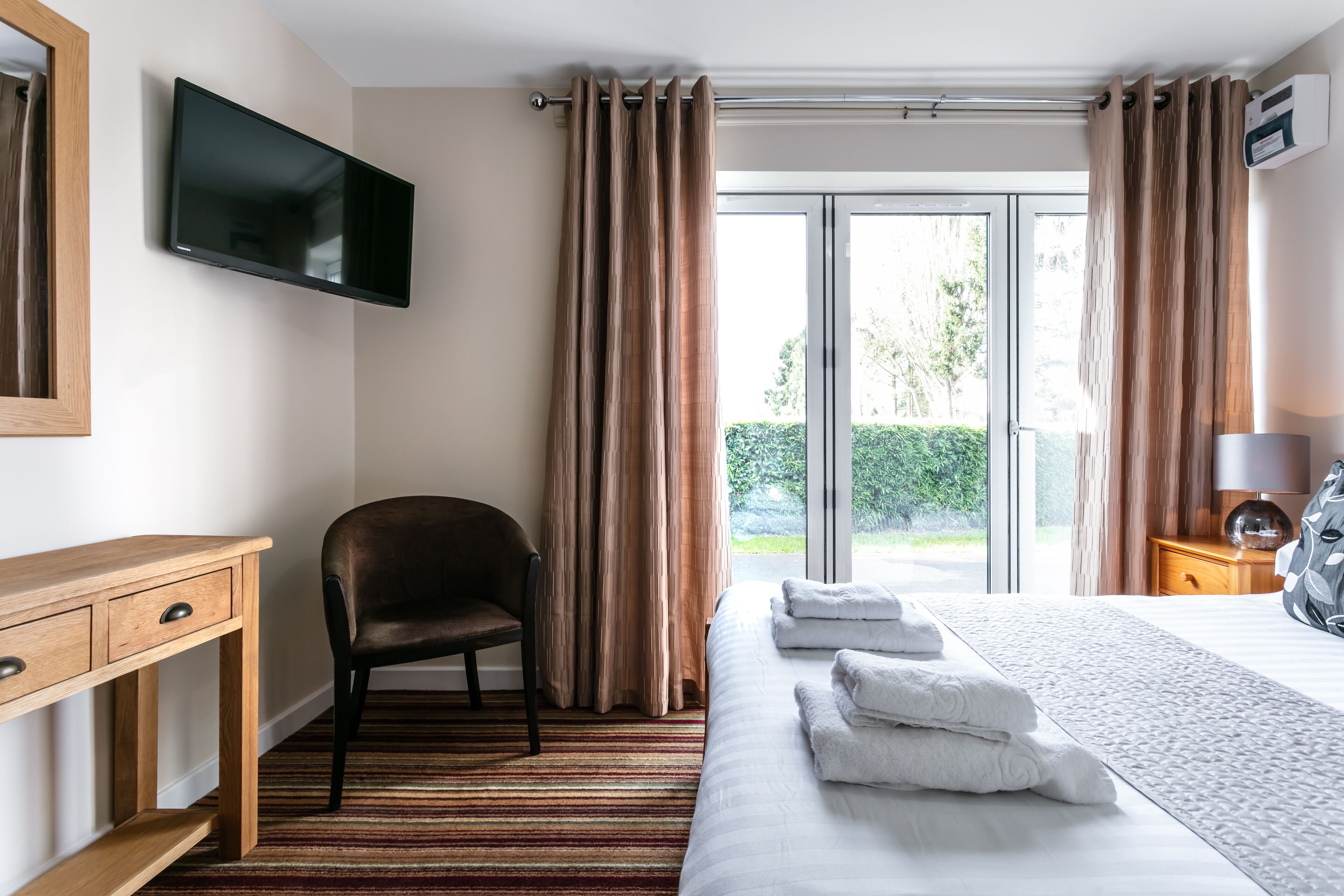 Une chambre d’hôtel équipée d’un lit, d’une chaise, d’un bureau, d’une télévision et offrant une vue sur l’extérieur.