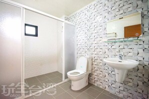 Une salle de bain avec des toilettes blanches, un lavabo en verre et un mur à motifs.