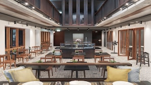 A spacious indoor area with multiple seating arrangements, including tables and chairs, and a central decorative element.