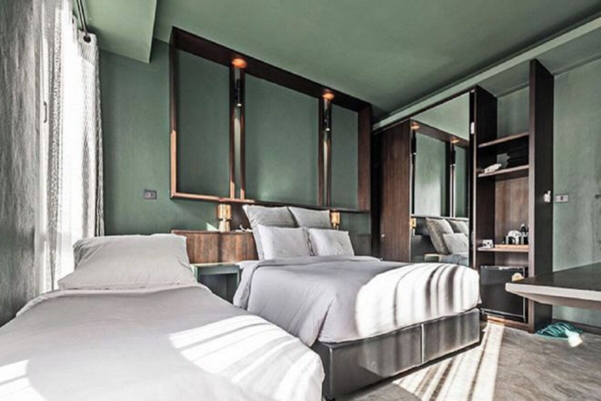 Una camera d'albergo moderna con un letto grande, un comodino, uno specchio e un tavolino rotondo.