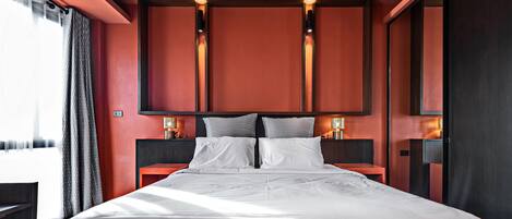 Una habitación de hotel moderna con una cama grande, dos mesitas de noche con lámparas y un espejo grande sobre la cama.