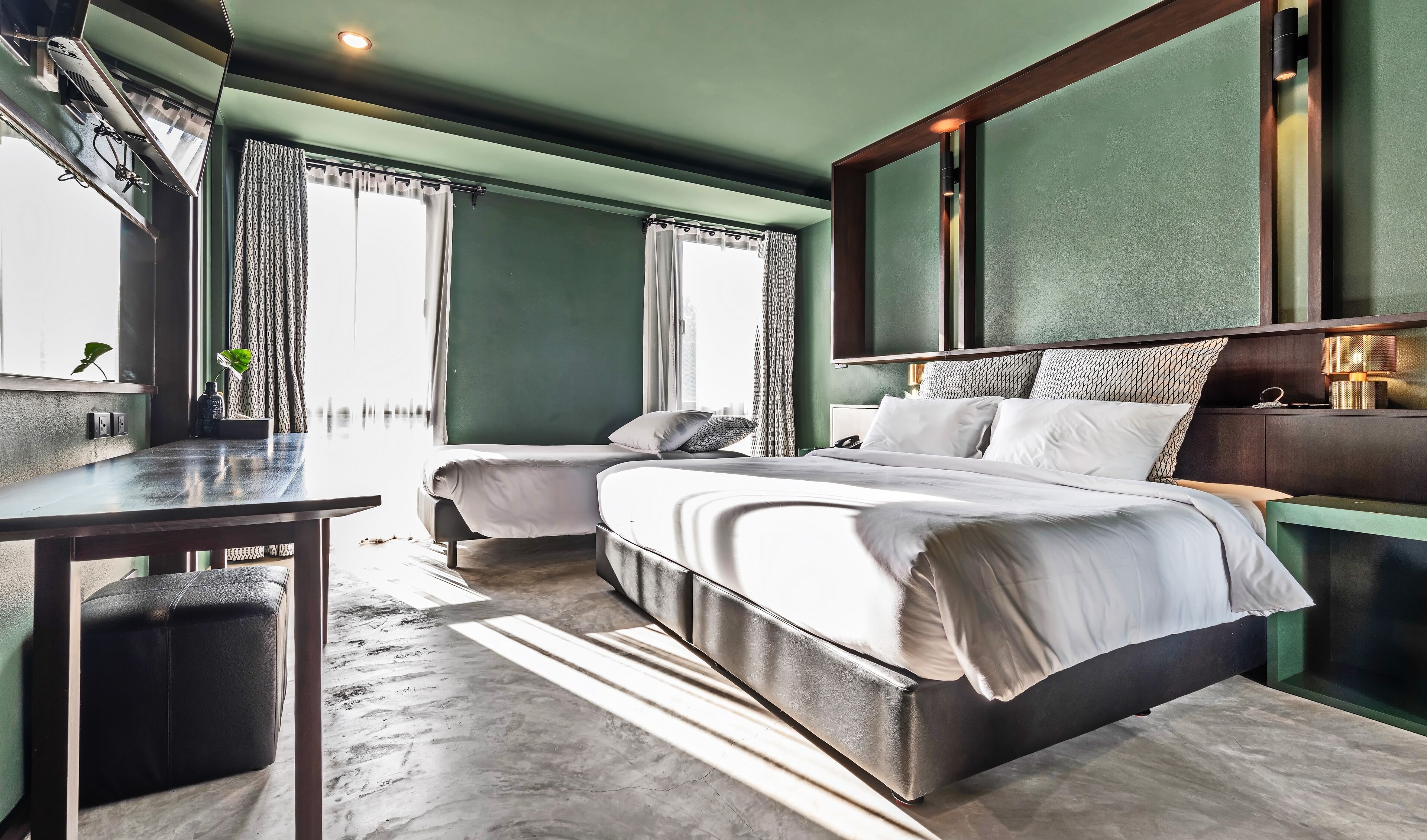 A modern hotel room with a large bed, two bedside tables, a desk, and a window with curtains.