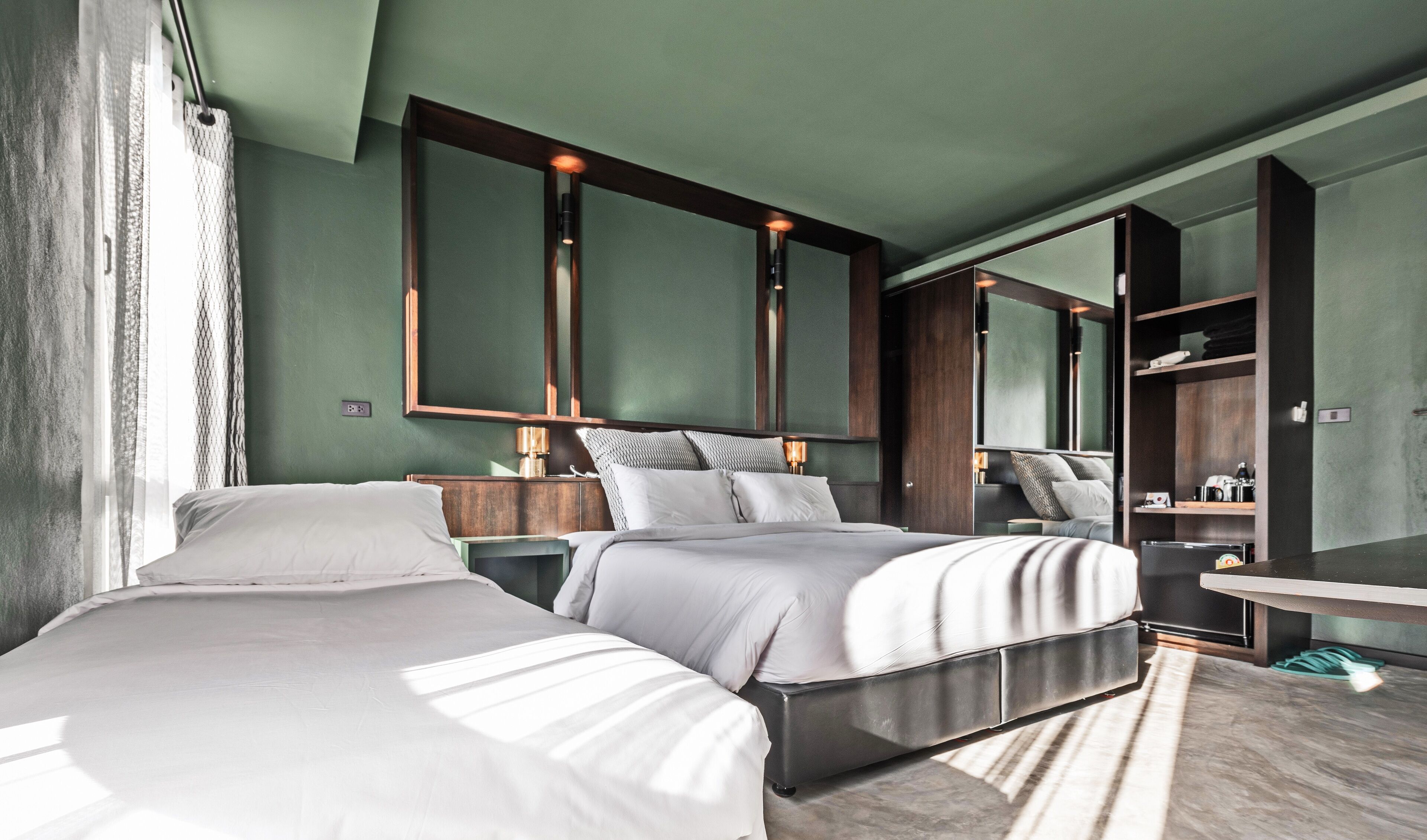 A modern bedroom with two beds, a large mirror, and a built-in wardrobe.