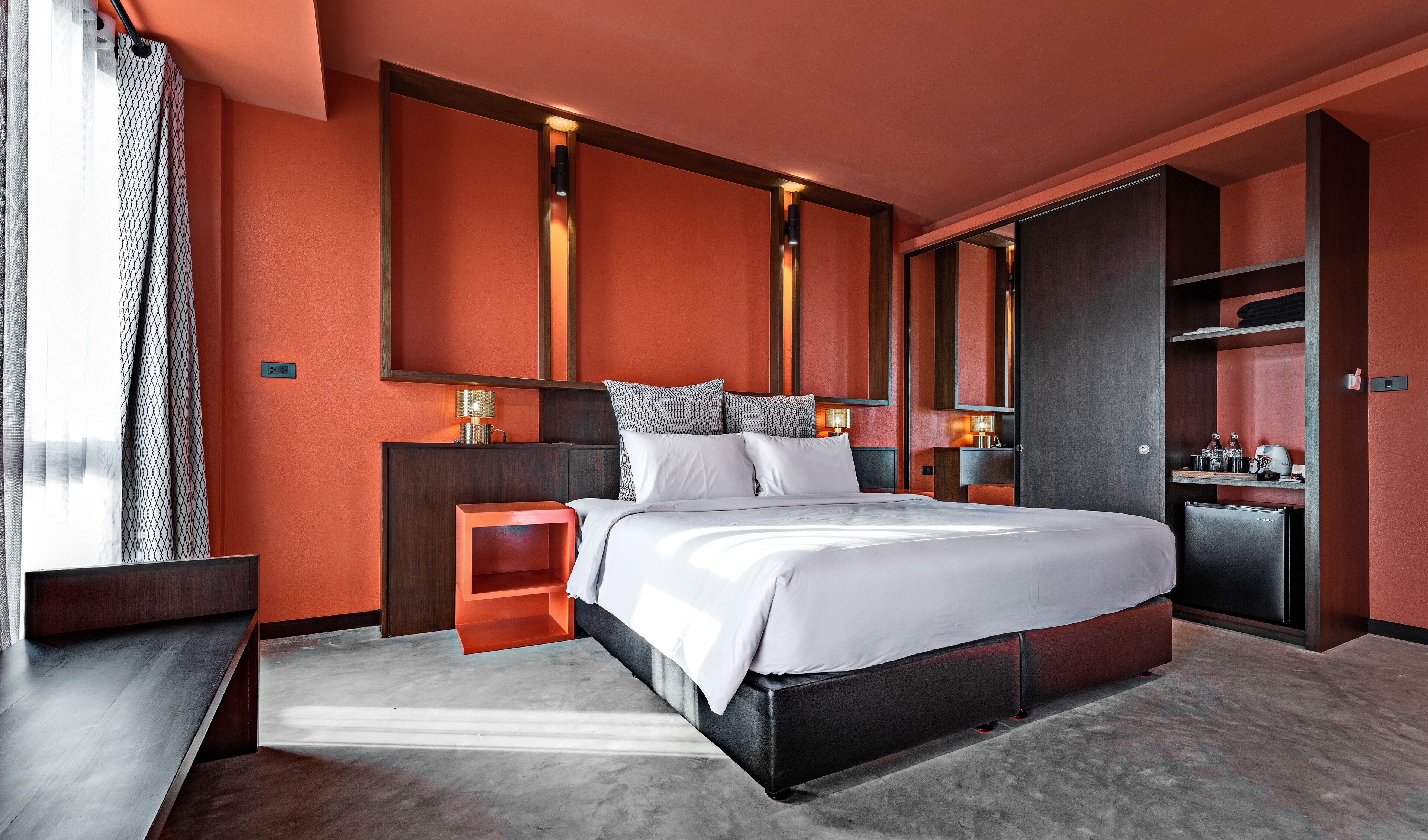 Une chambre d’hôtel moderne dotée d’un grand lit, de tables de chevet intégrées, d’une armoire et d’un coin salon avec une petite table.