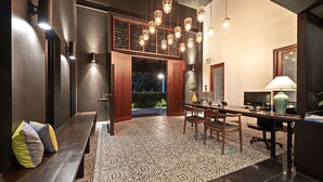 A modern dining area with a patterned floor, wooden furniture, and pendant lighting.