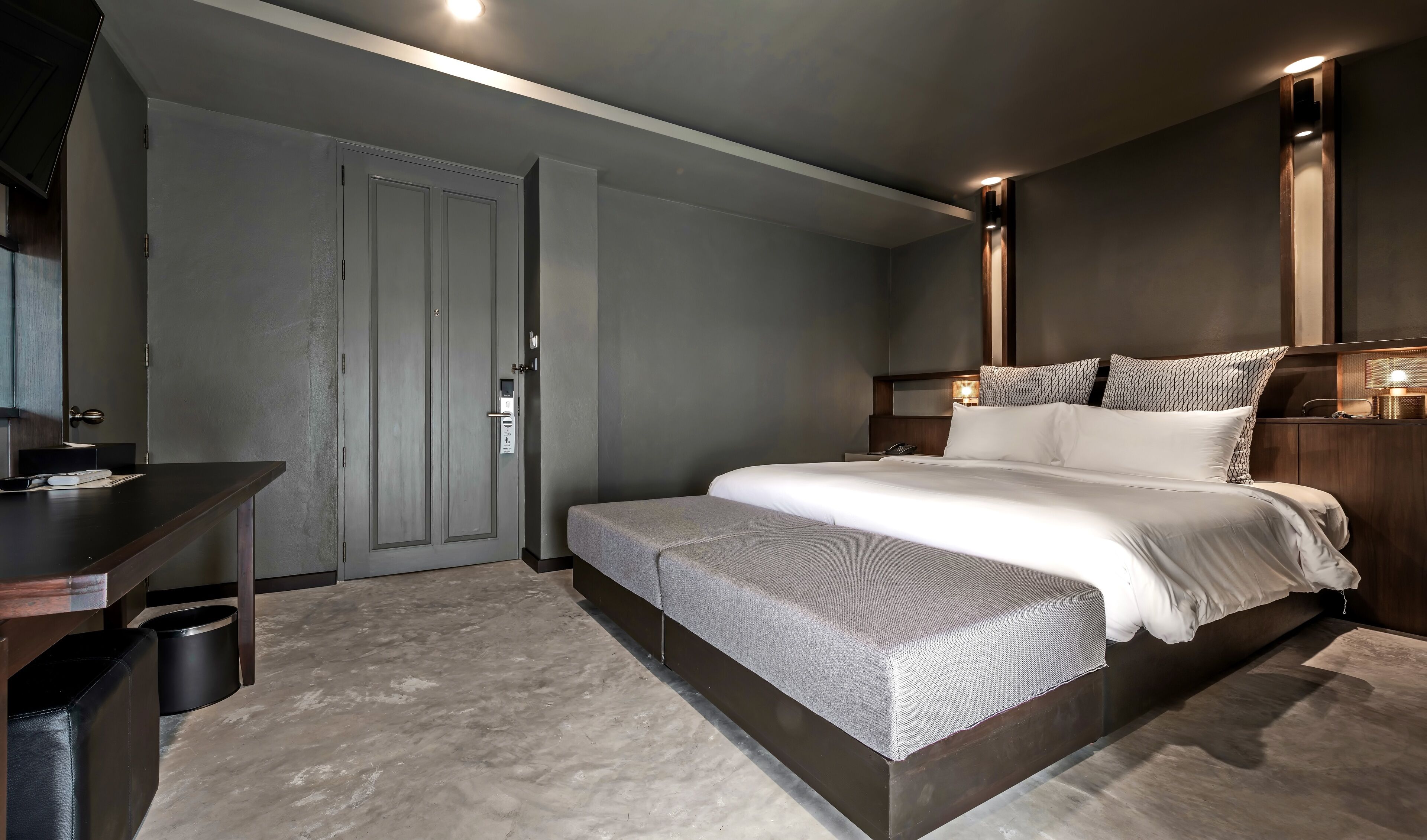 Un dormitorio moderno con una cama grande, mesitas de noche, un escritorio y un armario.