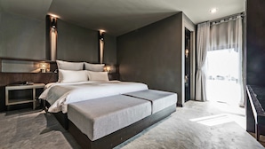 A modern bedroom with a large bed, bedside tables, and a view of the city through a window.