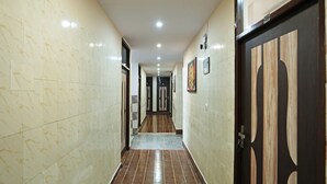 A hallway with marble walls and wooden flooring, leading to a door with a dark frame.