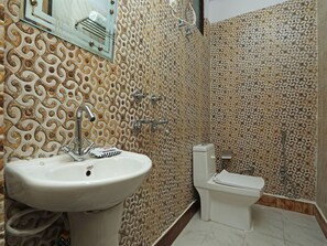 Un baño con lavamanos, inodoro y ducha. Las paredes presentan un diseño de azulejos estampados.