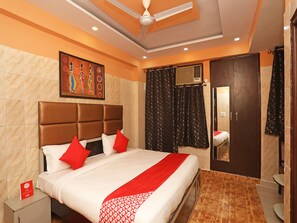 Habitación de hotel con una cama grande, ventilador de techo, un cuadro en la pared y una puerta con espejo.
