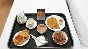 A tray with a teapot, cups, a plate of food, a bowl of soup, a plate of flatbread, a bowl of beans, and a napkin. - OYO 28028 Rishikul Sangam City (Karchana)