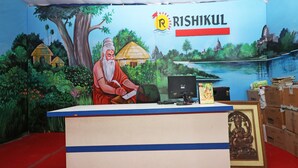 A reception desk with a mural of a serene landscape, a computer, and a framed statue. - OYO 28028 Rishikul Sangam City (Karchana)