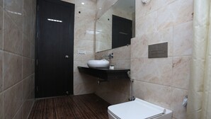 A modern bathroom with a dark door, a white sink, and a toilet. - OYO 27864 Hotel Samrat (Gurugram)