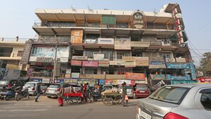 A multi-story building with various shops on the ground floor, including a hotel named 'Hotel Samrat'. - OYO 27864 Hotel Samrat (Gurugram)