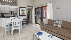 A modern living room with a brown sofa, a white coffee table, and a dining area with a white table and chairs. - San Lameer Villa  Rentals 2507 (Southbroom)