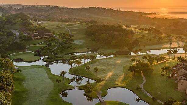 A golf course with multiple water hazards and a clubhouse. - San Lameer Villa  Rentals 2507 (Southbroom)