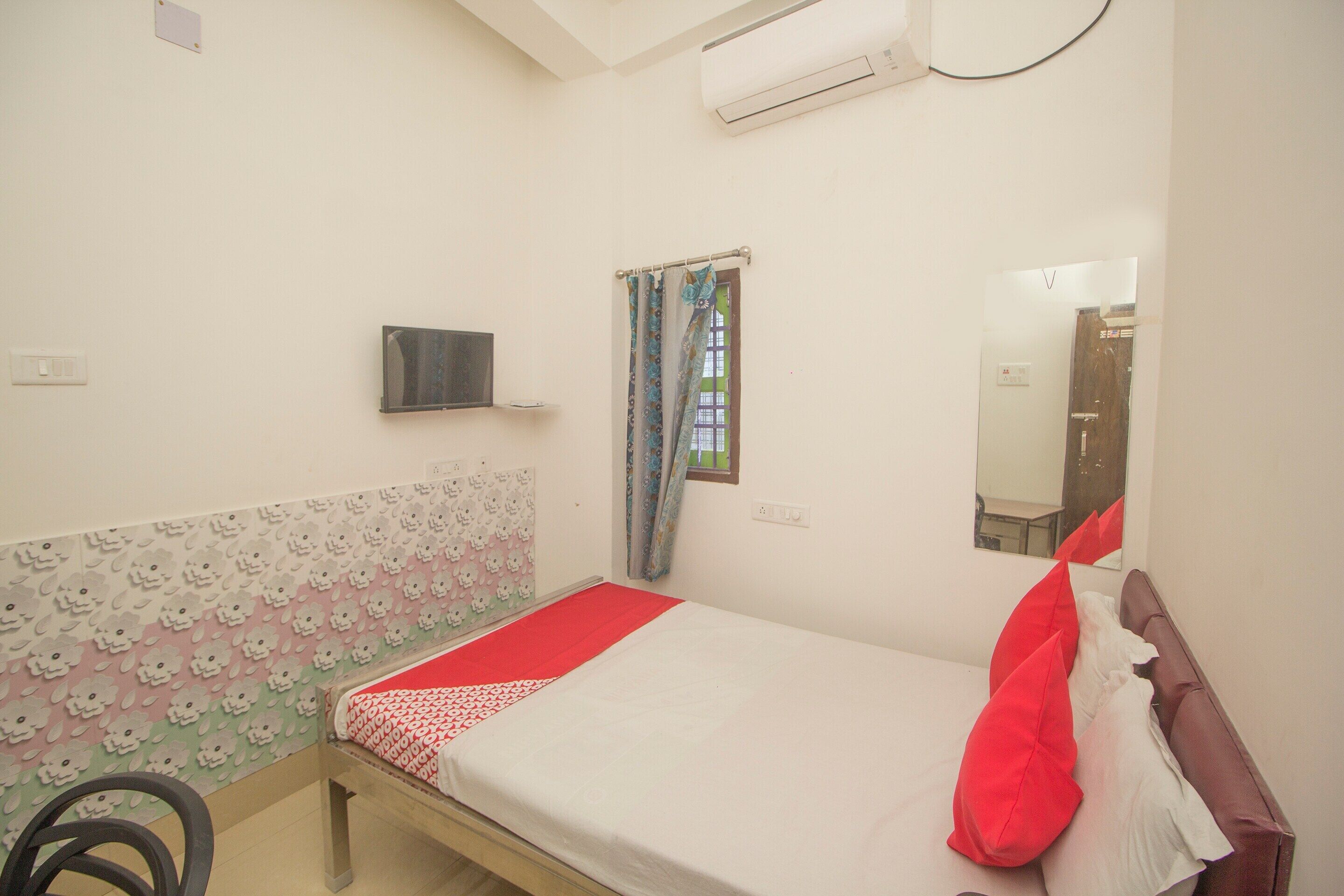 Un dormitorio con cama, televisor, ventana con cortinas y espejo.