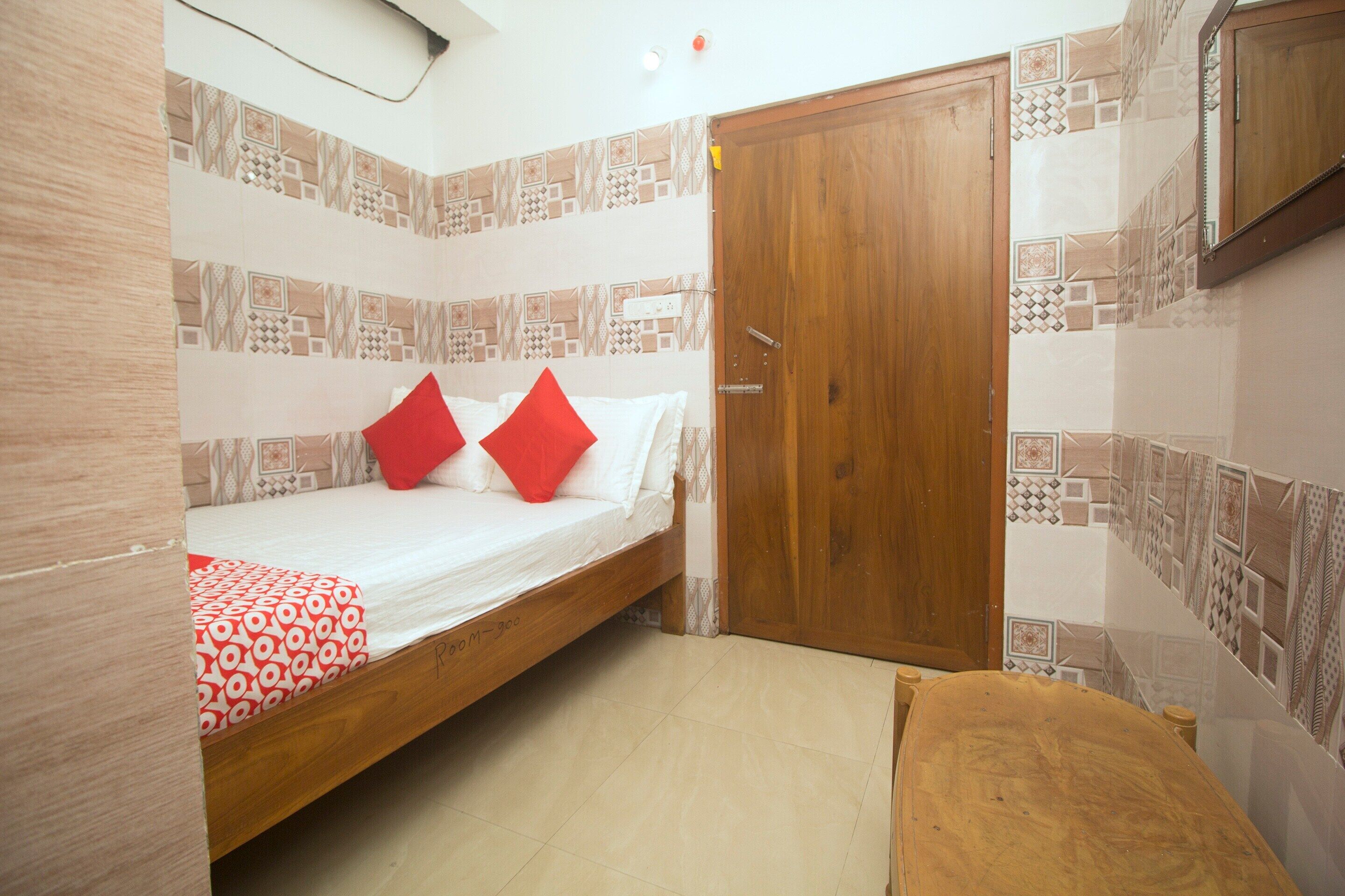 Una habitación con una cama, una puerta de madera y un papel tapiz estampado.