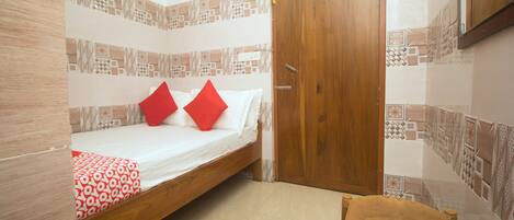 Una habitación con una cama, una puerta de madera y un papel tapiz estampado.
