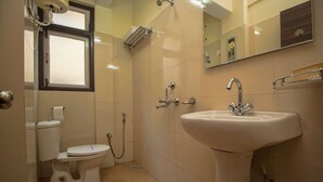 A bathroom with a toilet, bidet, sink, and a window.