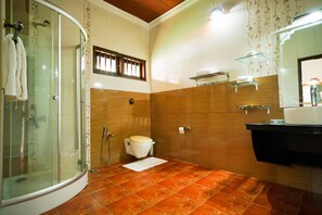 A bathroom with a glass shower enclosure, a toilet, and a sink area.