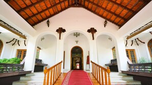 A grand hallway with a red carpet, wooden railings, and a high ceiling with exposed beams. - Palette Resorts- Tapovan Green County (Kothamangalam)