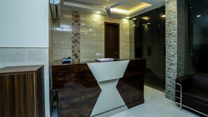 A modern reception desk with a geometric design, a ceiling fan, recessed lighting, and a textured wall.