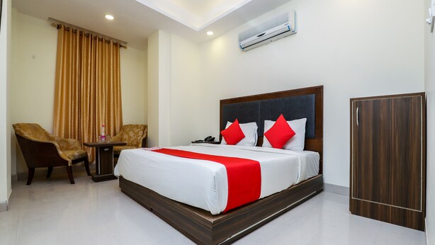 A hotel room with a large bed, a chair, a small table, and a wardrobe.