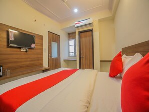Une chambre d’hôtel équipée d’un lit, d’un téléviseur fixé au mur, d’une fenêtre et d’un appareil de climatisation.