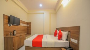 Habitació d'hotel moderna amb un llit de fusta, una televisió, una taula de nit amb un telèfon i un petit armari.