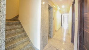 Passadís d'hotel amb escales de granit, paret de marbre i portes de fusta.