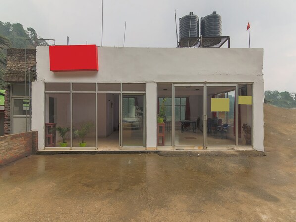 A building with a red section, large glass doors, and two water tanks on the roof.