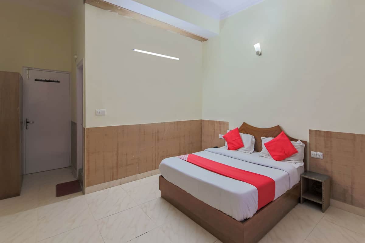 Een slaapkamer met een bed, nachtkastje, deur en een lamp.