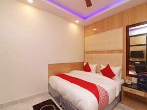 A hotel room with a large bed, a wooden headboard, a bedside table with a phone, and a mirror on the wall. - OYO 13774 Check In Room (New Delhi)