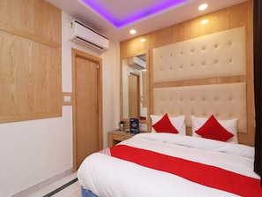 A hotel room with a bed, a nightstand, an air conditioning unit, and wooden paneling on the walls. - OYO 13774 Check In Room (New Delhi)