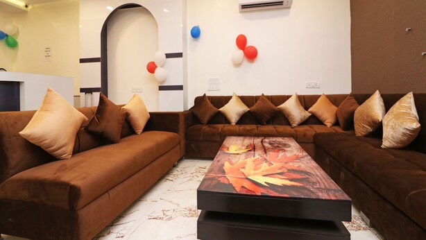 A modern living room with brown sofas, a central coffee table, and decorative balloons. - OYO 13774 Check In Room (New Delhi)