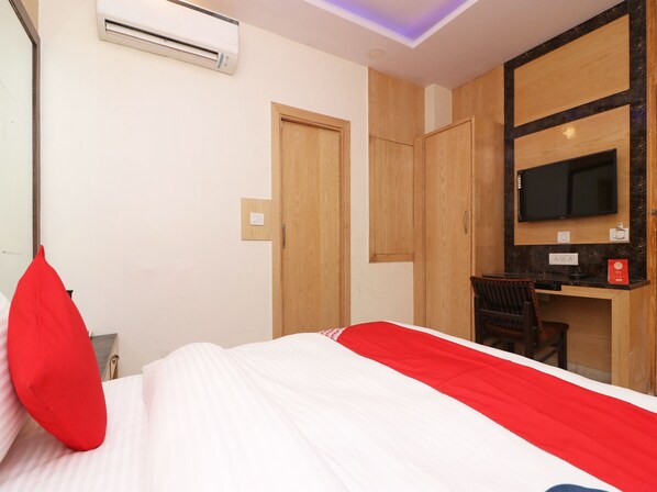 Une chambre d’hôtel équipée d’un lit, d’un bureau, d’une chaise, d’une télévision et d’un appareil de climatisation.