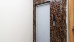 A closed elevator door with a marble wall and a wooden door frame. - OYO 13774 Check In Room (New Delhi)