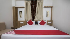 A neatly made bed with a red and white bedspread, two red pillows, and a wooden headboard. - OYO 15700 Spectrum Residency (Guwahati)