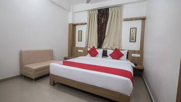 A bedroom with a bed, a nightstand, a chair, a ceiling fan, and curtains.