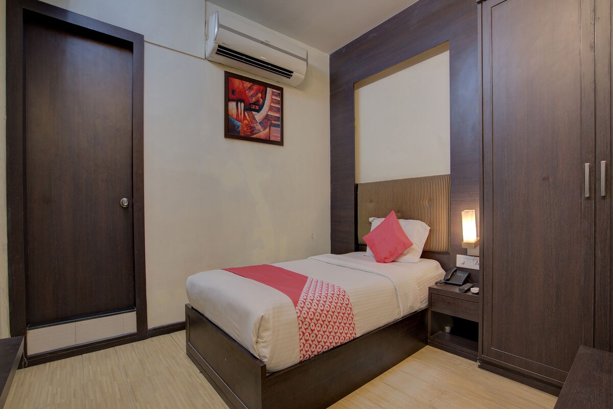 A hotel room with a bed, bedside table, nightstand, and a wardrobe.