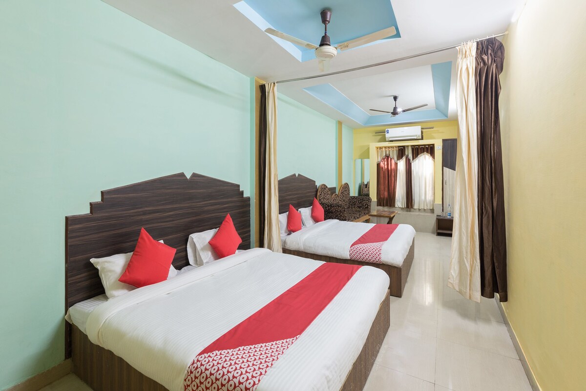 A hotel room with two beds, a ceiling fan, and a large window with curtains.